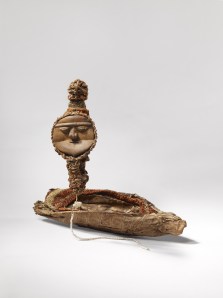 Monnaie et son étui. Milieu du XXe siècle. Bois, coquilles, cordonnet, fibres végétales tressées, feuilles séchées et poils de roussette. Dim. : Monnaie : 14,5 cm de haut. Étui : 23,5 x 6,5 x 4 cm. N° d’inv. : 71.1952.0.128 X. © musée du quai Branly, photo Claude Germain. 