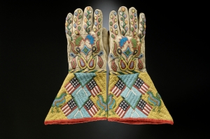Paire de gantelets, Sioux-Métis, Dakota du Nord ou du Sud, vers 1890. Les Indiens avaient découvert les gantelets par l’entremise des soldats de la cavalerie américaine, dans les années 1870. Éclatants de couleur, chaque manchette est ornée d’une croix formée de quatre drapeaux. Le décor floral abstrait est caractéristique du perlage des Sioux à la fin du XIXe siècle. Peau tannée, perles de verre et de laiton, tissu en coton. Dim. : 36,7 x 20 cm. © The Hirschfield Family Collection, Courtesy of Berte and Alan Hirschfield.