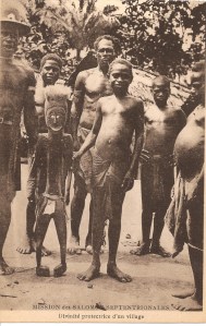 « Mission des Salomon Septentrionales. Divinité protectrice d’un village ». 13,7 x 8,8 cm. Portrait d’un groupe de salomonais du Nord avec une divinité protectrice. Cette figure des îles Buka ou de Bougainville est peut-être une représentation ancestrale urar généralement montrée lors de la cérémonie d’initiation upe. Au contraire des masques, forme d’expression inusuelle dans ces îles (à l’exception de Nisan et de Buka), les effigies anthropomorphes dominent l’art de l’ensemble de l’archipel.
