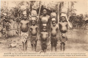 « Mission des Salomon Septentrionales – Groupe d’initiés à la Société secrète de l’esprit Toubouan. L’initié s’engage à fuir le contact des femmes aussi longtemps qu’il porte le chapeau, insigne de la Société secrète. ». 9,2 x 13,8 cm.