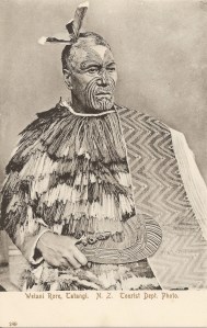 « Wetani Rore, Tatangi. N. Z. Tourist Dept. Photo. F. T. Series No. 189. ». 13,9 x 8 ,8 cm. Ce chef de l’iwi Ngati Maniapoto et Ngati Kahungunu, région de Waikato-Waitomo, au visage tatoué porte une cape avec une large bordure taniko et des plumes dans ses cheveux. Les courtes lignes tatouées sur le haut de son front indiqueraient qu’il était “maître d’armes”. L’Auckland War Memorial Museum Library (Catalogue GN672.2 T2) possède une photographie (vers 1870), similaire à celle utilisée pour cette carte postale, attribuée au photographe George Pulman, spécialisé dans les portraits maori.